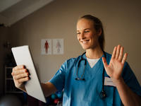 Female doctor smiling while holding a tablet device