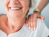 Older woman with nurse's hand on her shoulder